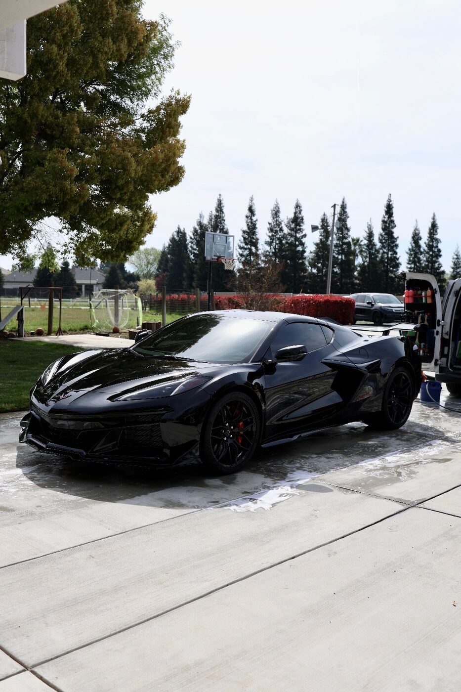 Black Corvette Z06 with a deep, glossy finish on a wet driveway